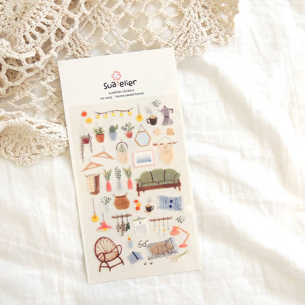 Suatelier Home Sweet Home boho decor sticker sheet with illustrated rattan chair, green sofa, string lights, plants, vases, picture frames, and sleeping cat, made in South Korea
